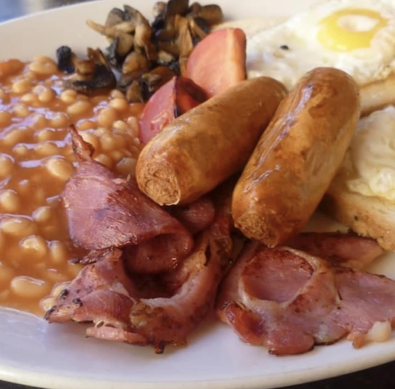 Full breakfast plate with bacon, sausage, eggs, beans and mushrooms
