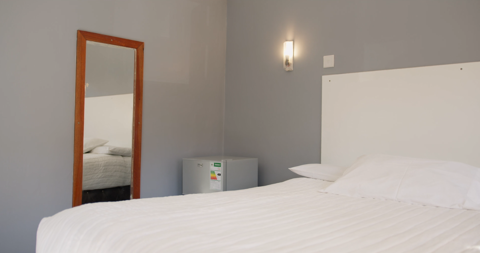 Bedroom with mirror and mini fridge at the Moto Moto branch